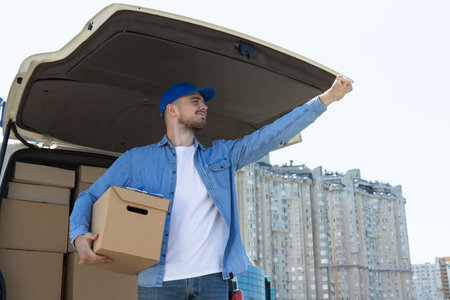A courier with a box in his hands near a car with boxes