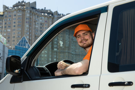 A smiling courier carrying parcels by car
