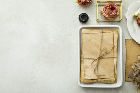 Old letters, white plates, roses, ink bottle and pen on light background, space for text