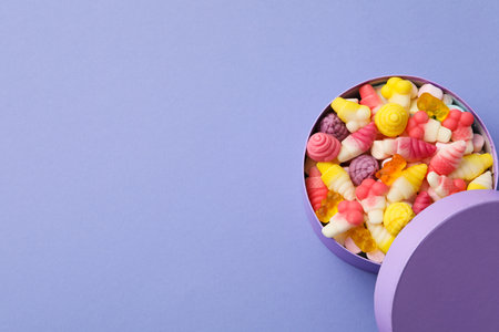 Jelly candies in box on purple background, space for textの写真素材