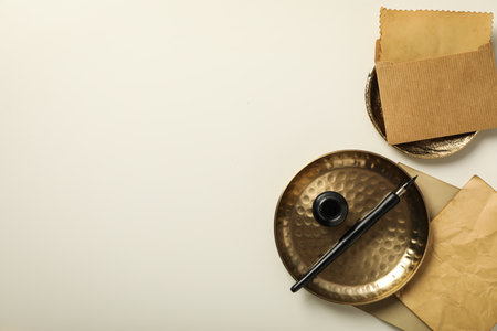 Old letters, golden plate, ink bottle and pen on light background, space for textの写真素材