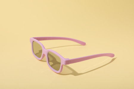 Light pink glasses with tinted lenses on beige background