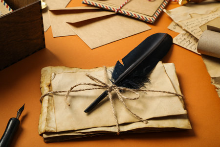Old letters, feather and wooden box on orange backgroundの写真素材