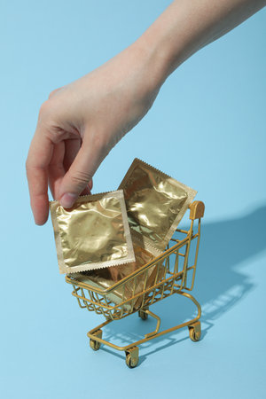 Condoms in a shopping cart on a blue backgroundの写真素材