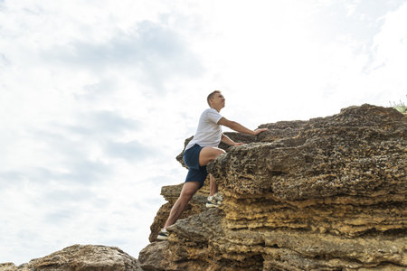 A man with an athletic build climbs to the top of a rockの写真素材