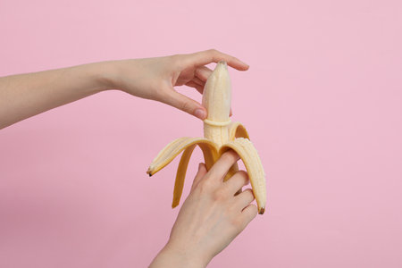 Condom on banana in hand on light backgroundの写真素材