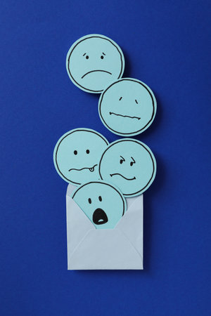 Envelope, papers with sad emoji on dark blue background, top viewの写真素材
