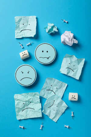 Papers and marshmallows with sad emoji on blue background, top viewの写真素材