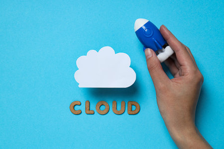 White paper cloud with a toy rocket and the word cloud on a blue background