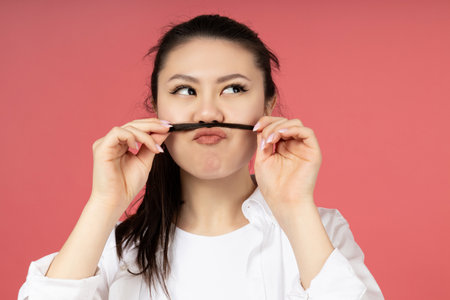 An Asian girl made a mustache from her own hair on her headの写真素材
