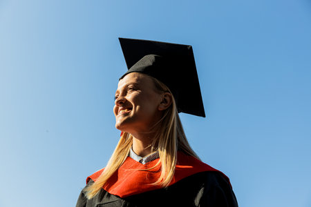 Smiling young woman in mantle and hat against the skyの写真素材