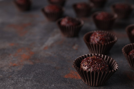 Brigadeiro in paper forms on dark background, space for text