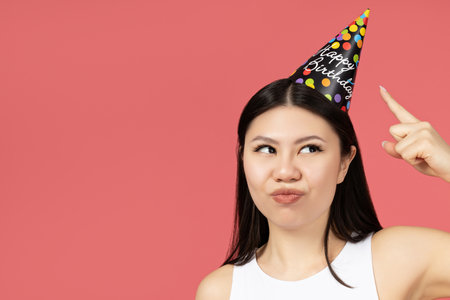 Asian girl with a holiday cap on her head, pointing with her fingerの写真素材