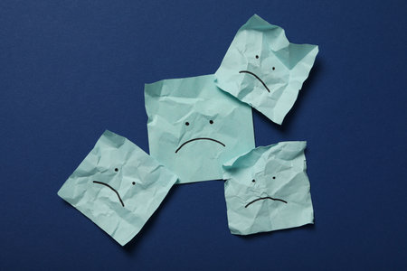 Papers with sad emoji on blue background, top viewの写真素材