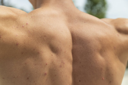 A sporty man demonstrates his back muscles, close-upの写真素材