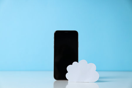 Black smartphone with paper white cloud on a blue backgroundの写真素材