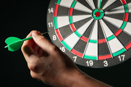 Darts hitting the target on a dark background.の写真素材