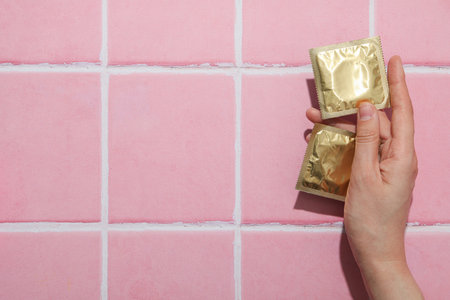 Condoms in hand on pink background, place for textの写真素材
