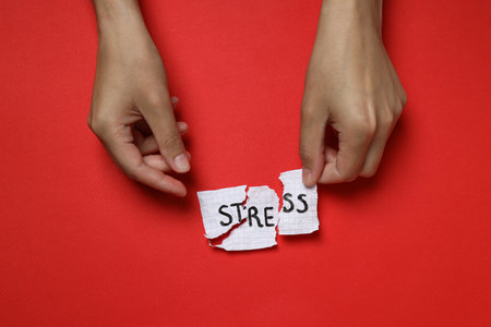 Paper with word Stress and hands on red background, top viewの写真素材
