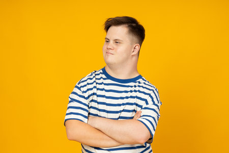 Smiling young man with cerebral palsy in glasses in a striped t-shirt on a yellow background. World Genetic Diseases Day conceptの写真素材