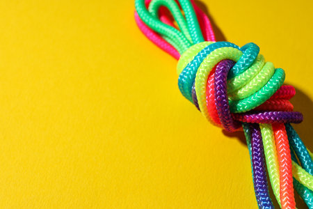 A knot of multi-colored laces on a yellow background. Place for textの写真素材