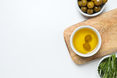 Olive branches, oil and olives in bowls, kitchen board on white background, space for textの写真素材