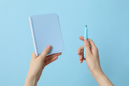 Female hands hold a notebook and a felt-tip penの写真素材