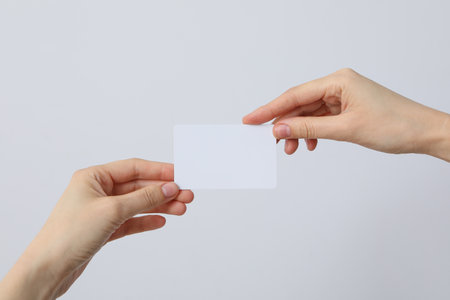 A white blank sheet of paper in the hands of a woman on a light backgroundの写真素材