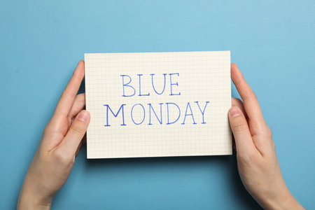 Paper with text Blue Monday in female hands on blue background, top viewの写真素材