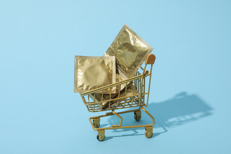 Condoms in a shopping cart on a blue backgroundの写真素材