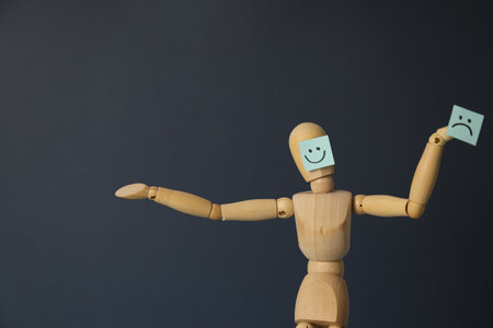 Wooden doll with a sad and cheerful face, bipolar disorder concept, place for text