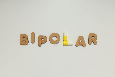 The word "bipolar" with yellow pills on a light backgroundの写真素材