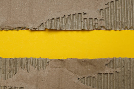Torn cardboard on a yellow background, top view.の写真素材
