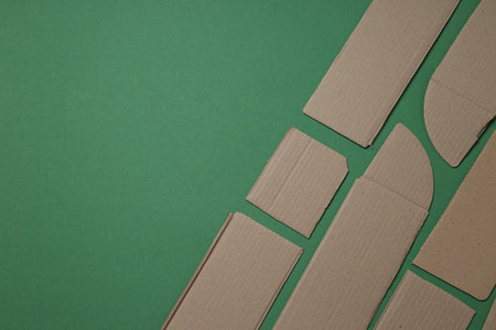 Torn cardboard on a green background, top view. Garbage recycling concept.の写真素材