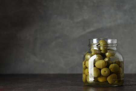 Olives in jar on gray background, space for textの写真素材