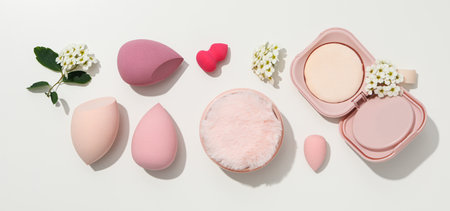 Cosmetic sponges, powder and flowers on white background, top viewの写真素材