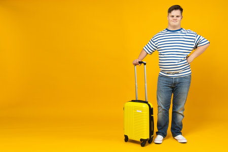 Smiling young man with down syndrome with suitcase, place for textの写真素材