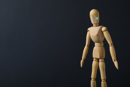 Wooden man on dark blue background, space for text