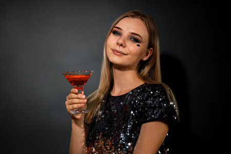 A girl at a party in the style of Halloween with a cocktail in her handsの写真素材