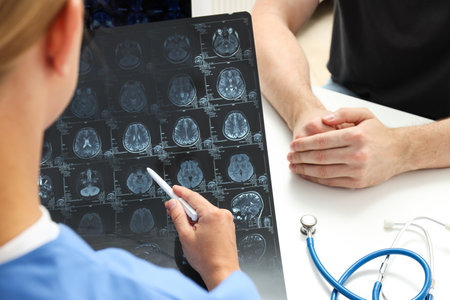 A young female doctor is looking at an MRI image of a human headの写真素材