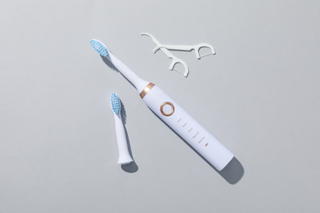 Electric toothbrushes and dental floss on gray background, top viewの写真素材