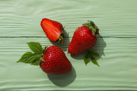 Strawberries with leaves on green wooden background, top viewの写真素材