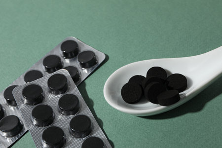 Activated charcoal tablets in a white spoonの写真素材
