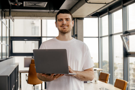 Happy young entrepreneur smiling with laptop in hands in coworking spaceの写真素材
