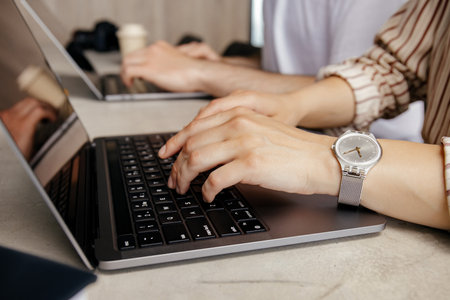 Female hands on black laptop keyboard close-up