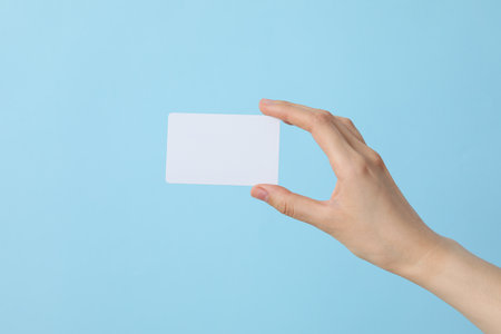 A white blank sheet of paper in the hands of a woman, on a blue backgroundの写真素材
