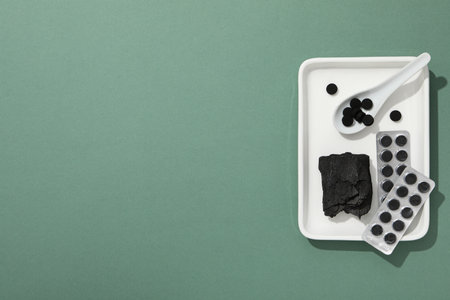 Activated charcoal tablets with a spoon in a white bowl