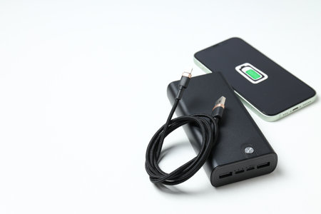 Powerbank, smartphone and cord on white background, space for text