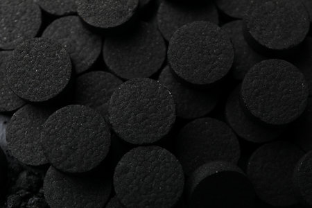 Pile of black activated charcoal pills close-up
