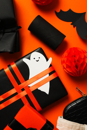 Gift boxes, paper ghost and bat on orange background, top viewの写真素材